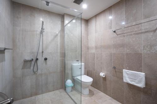 a bathroom with a toilet and a glass shower at Modern 1-Bed Unit with Pool Views and Balcony in Canberra
