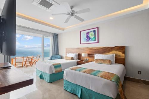 two beds in a hotel room with a view of the ocean at Blue Horizon Luxury Condo in Puerto Vallarta