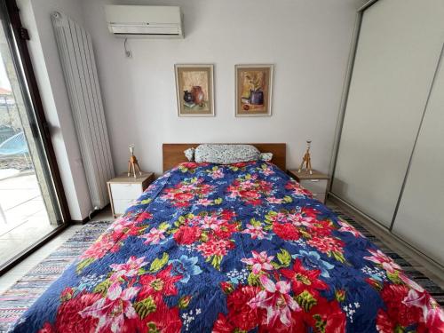 una camera con un letto con una coperta floreale di Kazanlak LARGE GUEST HOUSE Apartment near Center with Full Kitchen & Dining Room, King Beds, Garden Patio, Free Parking & Self Check-in Top Value! a Kazanlŭk