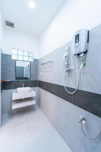 a bathroom with a shower with a sink and a mirror at Nine Homestay in Can Tho