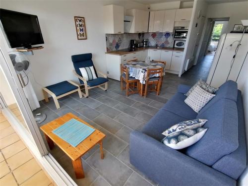 un salon avec un canapé bleu et une table dans l'établissement Appartement refait 2 pièces avec piscine et parking - FR-1-731-106, au Grau-du-Roi