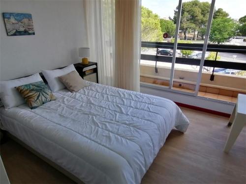 une chambre avec un lit et une grande fenêtre dans l'établissement Appartement refait 2 pièces avec piscine et parking - FR-1-731-106, au Grau-du-Roi