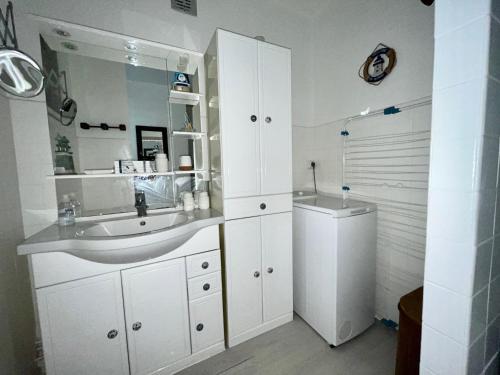 une salle de bain blanche avec un lavabo et un miroir dans l'établissement T2 à Saint-Cyprien, proche port, parking inclus - FR-1-309-480, à Saint-Cyprien