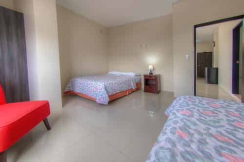 a hotel room with two beds and a red chair at Galapagos Dreams in Puerto Ayora