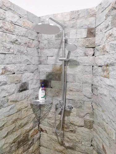 a shower in a bathroom with a stone wall at Cornerstone dive center in Tulamben
