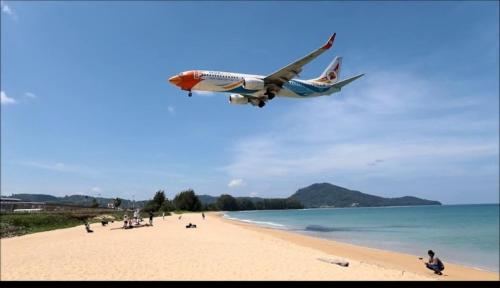 a plane flying over a beach with people on it at Haru Inn Airport in Ban Bo Han