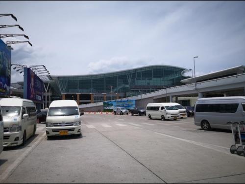 a parking lot with cars parked in front of a building at Haru Inn Airport in Ban Bo Han