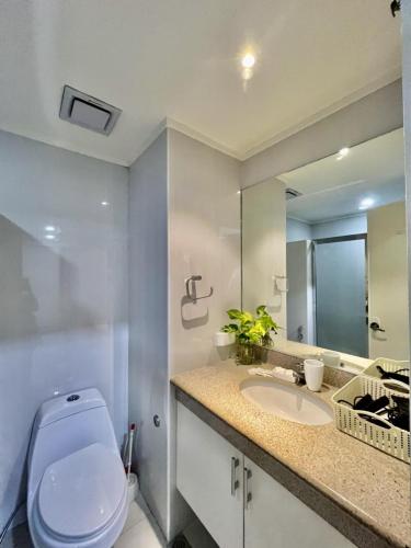 a bathroom with a toilet and a sink and a mirror at Kelsey's Homestay at Magallanes Residences Condominium in Davao City