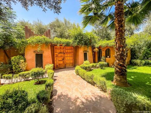 a house with a palm tree and a driveway at Villa Atlas Secret in Ourika