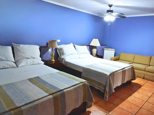 a blue room with two beds and a couch at Hotel Puerta del Sol - San Jose Airport in San José