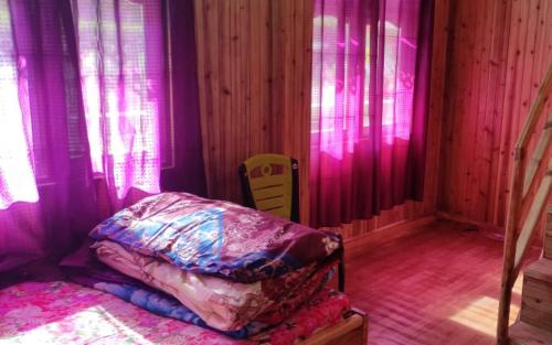 a bedroom with pink and purple curtains and a bed at Green Wings Homestay Sittong by StayApart in Mangpu