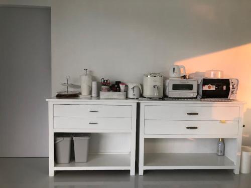 a white counter with a microwave and a toaster oven at Takraw Rim Kwae ตะคร้อริมแคว in Ban Pong Pat