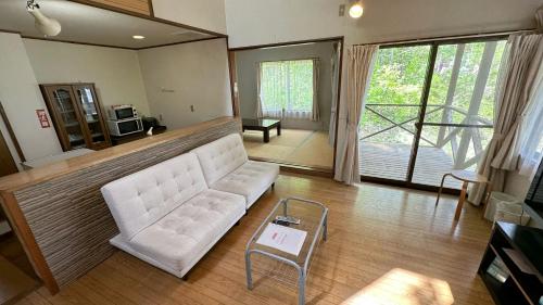 a living room with a white couch and a table at Nature Cottage Akabeko in Kitashiobara