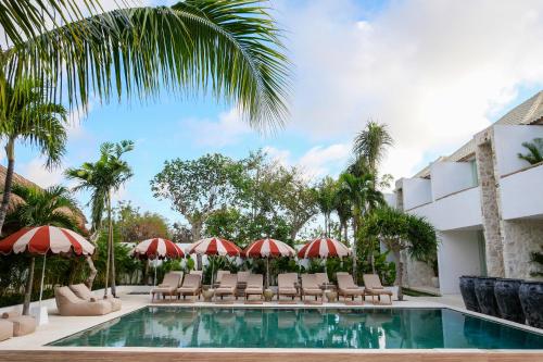 a resort pool with chairs and umbrellas at The Balangan Hotel in Jimbaran