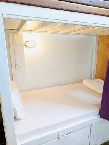 a small white room with a bed in it at The Siem Reap Chilled Backpacker in Siem Reap