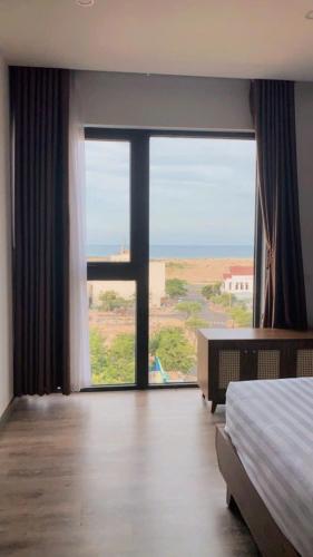a bedroom with a bed and a view of the ocean at LaLa Apartment and Hotel in Danang