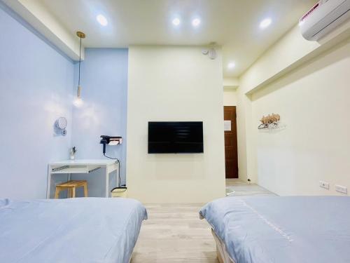 a room with two beds and a tv on a wall at 星月織旅-屏東潮州包棟民宿 in Chaozhou