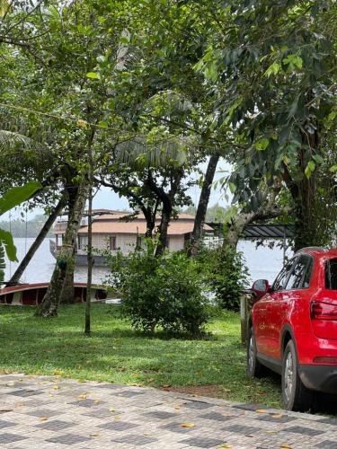 a red car parked next to a body of water at AshtamudiVillas in Kollam
