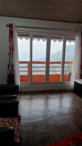 a living room with large windows with a view at Lotus Homestay in Darjeeling