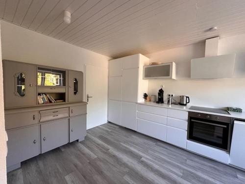 a kitchen with white cabinets and a wooden floor at Ferienhaus chez nous in Merzig