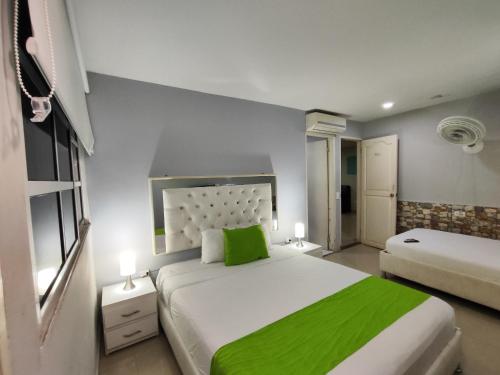 a bedroom with two beds with green sheets and lamps at Hotel Casa Bellamare in Cartagena de Indias
