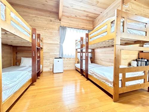 a room with three bunk beds in a cabin at Furano Log House Farm Resort in Furano
