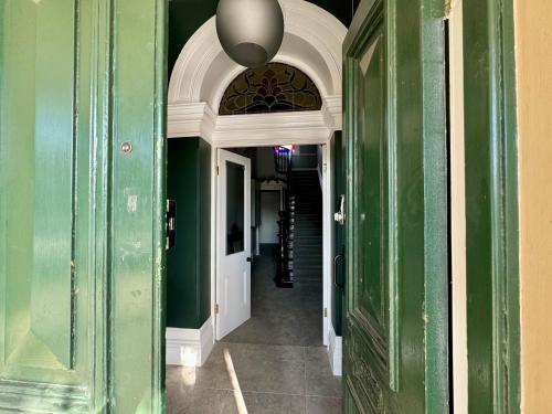 a hallway in a building with green walls and an archway at Treehouse Hideouts Balcony Apartment - Port of Echuca Townhouse in Echuca