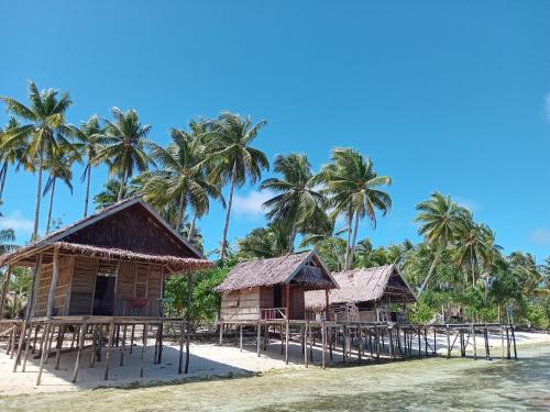 a group of bungalows on a beach with palm trees at Fam Homestay in Fam