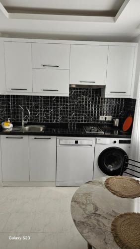 a kitchen with white cabinets and a sink and a table at Aygun Apart 4 in Mahmutlar