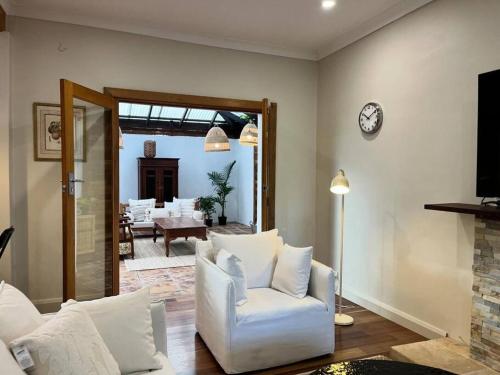 a living room with a white chair and a clock at Tranquil Hideaway near the City- with Patio Lounge in Glenunga