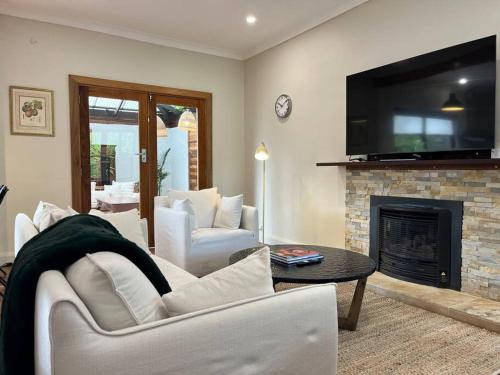 a living room with white furniture and a fireplace at Tranquil Hideaway near the City- with Patio Lounge in Glenunga