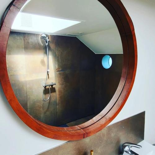 a circular mirror above a sink in a bathroom at Une perle ! Péniche complète pour 8 sur la Meuse, région Namur in Andenne