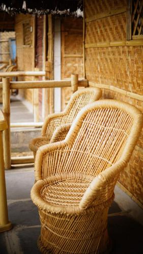three wicker chairs lined up against a brick wall at Anu Guest House in Hampi
