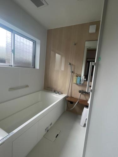 a white bathroom with a tub and a sink at Retreat Guest House Surya - WOMEN's only - in Kawazu