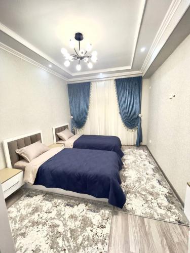 a bedroom with two beds and blue curtains at Harmony Homestay in Samarkand
