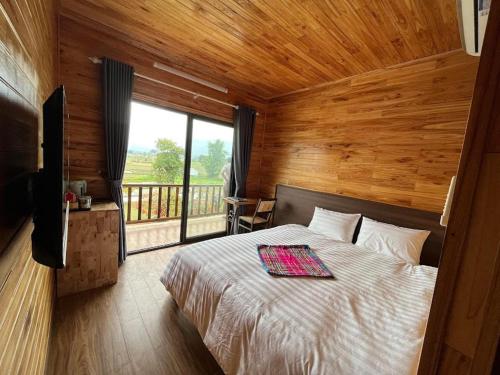 a bedroom with a bed and a large window at Trần Gia Homestay in Văn Chấn