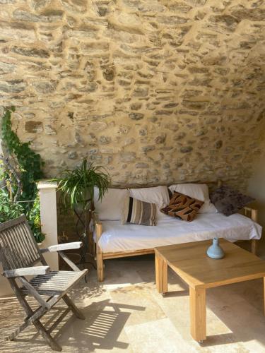 un lit et une chaise en face d'un mur en pierre dans l'établissement Appartement dans maison de village provençal, à Château-Arnoux-Saint-Auban