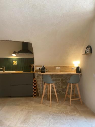 - une cuisine avec un comptoir et deux tabourets dans une pièce dans l'établissement Appartement dans maison de village provençal, à Château-Arnoux-Saint-Auban