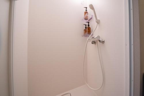 a shower with a shower head hanging on a wall at LOCO Minamiichi in Nara