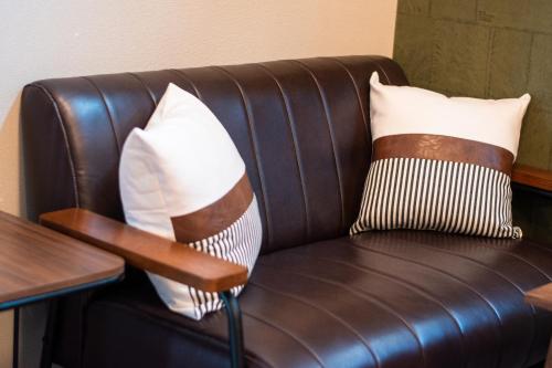 a brown leather couch with two pillows on it at LOCO Minamiichi in Nara