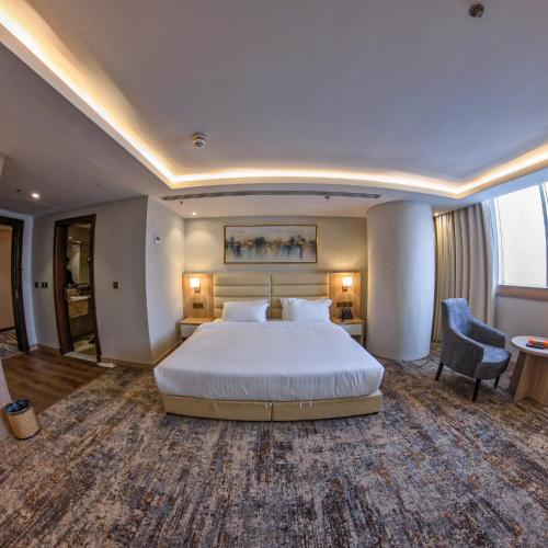 a large hotel room with a bed and a chair at Samtinn Hotel King Fahad in Riyadh