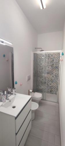a white bathroom with a toilet and a shower at Donna Beatrice aMare beach house in Donnalucata