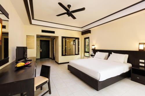 a bedroom with a bed and a desk and a television at Nang Thong Beach Resort in Khao Lak