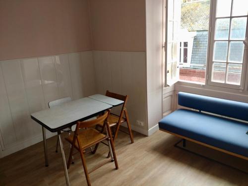 une chambre avec une table, des chaises et un banc dans l'établissement Appartement Le Tréport, au Tréport