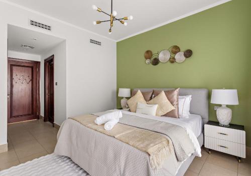 Un dormitorio con una cama y una pared verde. en 5 Min Walk to Burj Khalifa 2BHK Luxury Downtown Burj Haven, en Dubái