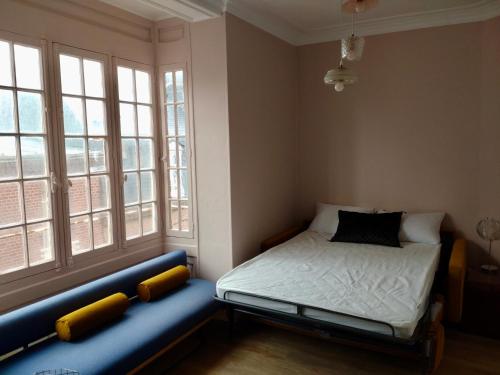 une petite chambre avec un lit et deux fenêtres dans l'établissement Appartement Le Tréport, au Tréport