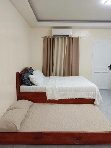 two twin beds in a bedroom with a window at Wyne's Tiny House near Royal Farm Resort in Dipolog