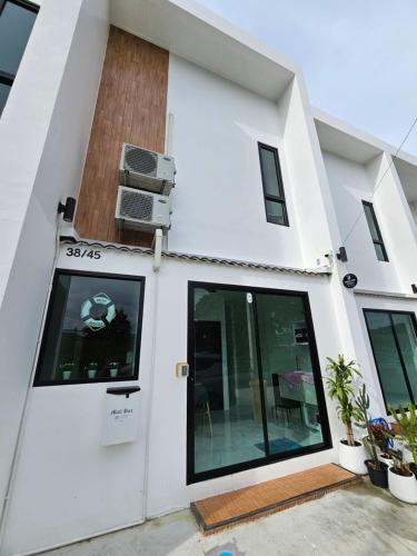 a white house with a door and a fan at Haru Inn Airport in Ban Bo Han