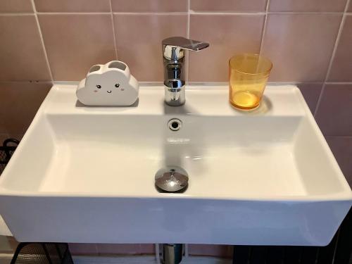 un évier blanc avec une tasse et un verre dans l'établissement Appartement Le Tréport, au Tréport