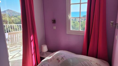 Un dormitorio con paredes moradas y una ventana con cortinas rojas. en AGAY, Cap Esterel, magnifique vue mer panoramique et Esterel, terrasse, piscines, parking, dernier étage, 3 étoiles, en Saint-Raphaël